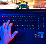 Person typing on an illuminated keyboard with glowing backlight